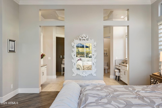 bedroom with crown molding, ensuite bath, light wood-style flooring, and baseboards