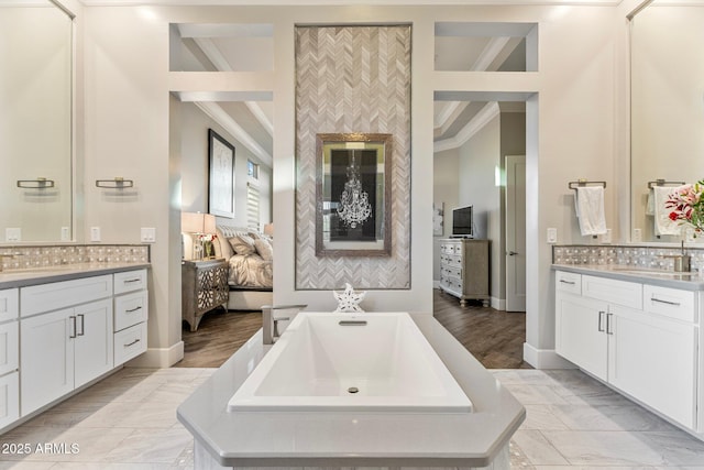 full bathroom with a freestanding tub, two vanities, a sink, and backsplash