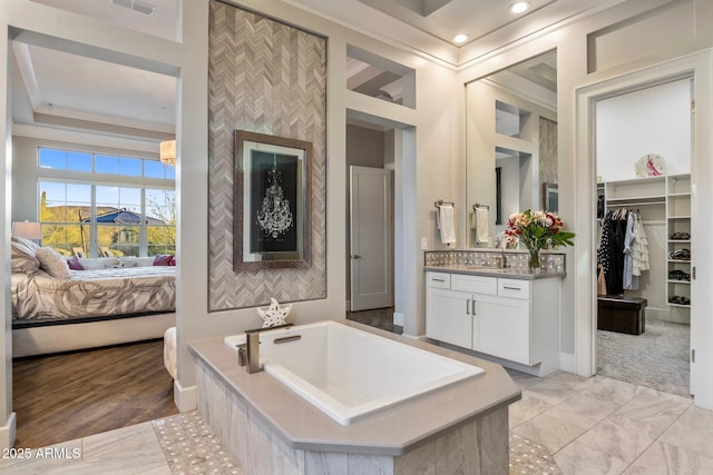 full bath with ensuite bathroom, a garden tub, vanity, a spacious closet, and ornamental molding