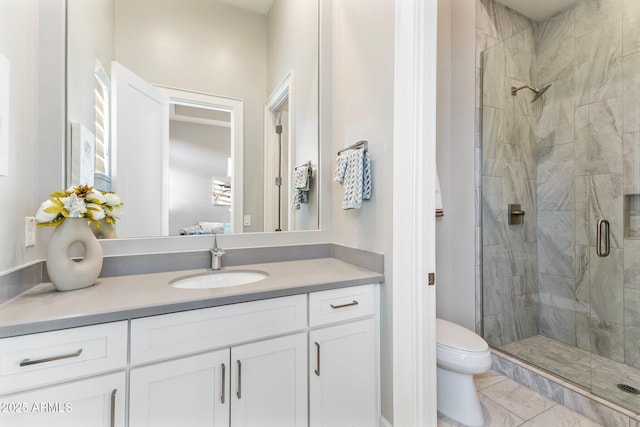 ensuite bathroom featuring tile patterned floors, a shower stall, toilet, and vanity