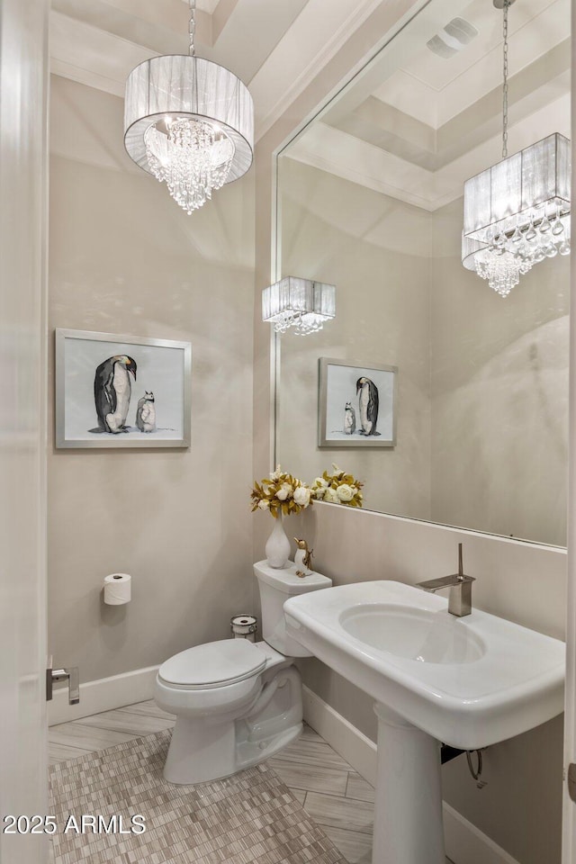 bathroom featuring toilet, baseboards, and a notable chandelier