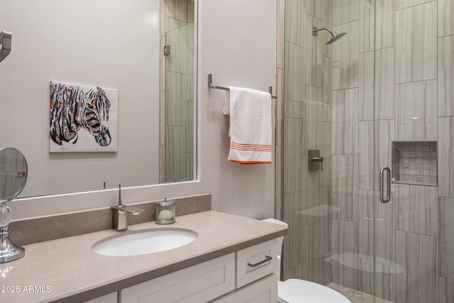 bathroom with toilet, a stall shower, and vanity