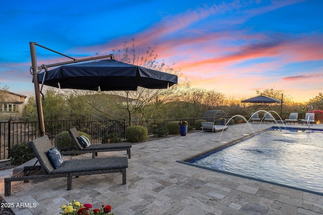 pool at dusk with fence and a patio