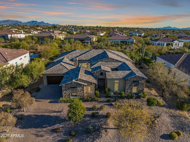 view of front of property with decorative driveway, a mountain view, a garage, a residential view, and stone siding