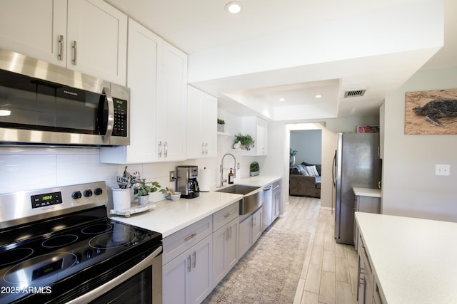 8135 N Central Ave Unit 1, Phoenix, AZ 85020 - kitchen with appliances with stainless steel finishes, a sink, light countertops, a tray ceiling, and recessed lighting
