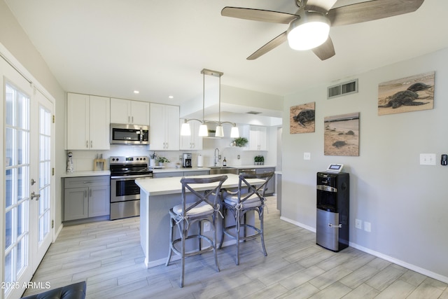 8135 N Central Ave Unit 1, Phoenix, AZ 85020 - kitchen with stainless steel appliances, light countertops, a sink, a kitchen bar, and light wood finished floors