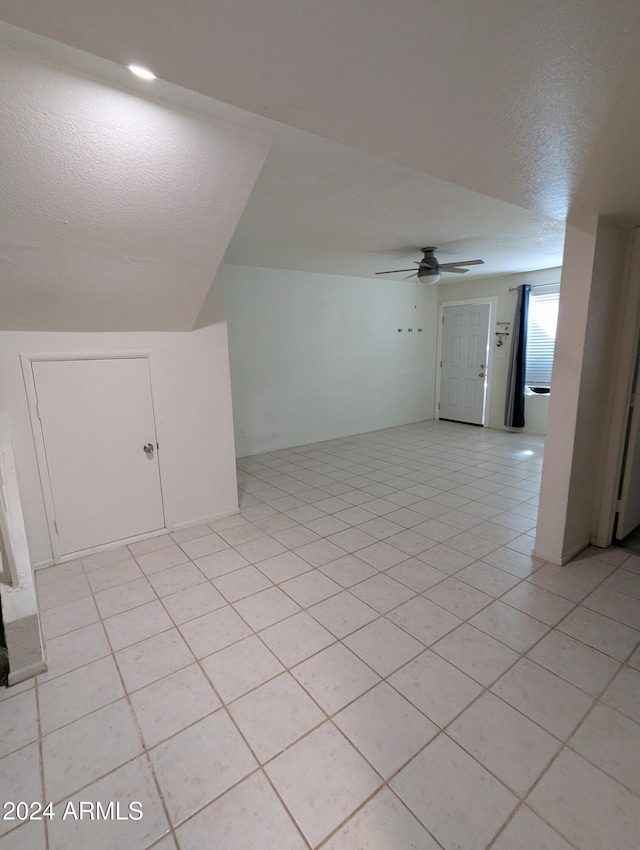 bonus room featuring ceiling fan, light tile patterned floors, and a textured ceiling