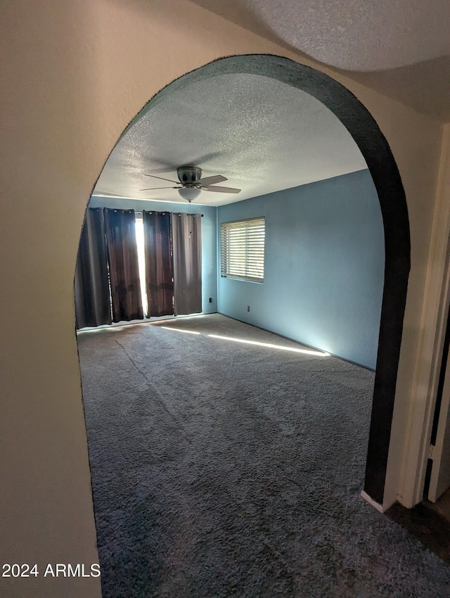 carpeted spare room featuring ceiling fan and a textured ceiling