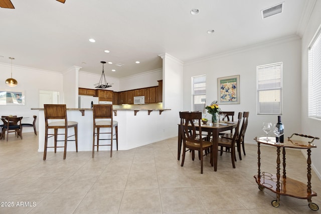 tiled dining room featuring plenty of natural light and ornamental molding