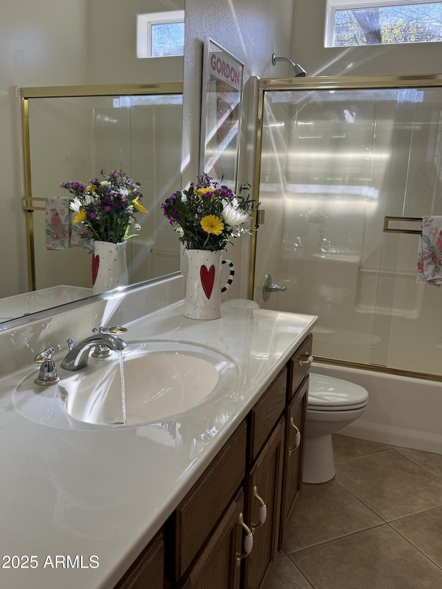 full bathroom with tile patterned floors, plenty of natural light, toilet, and bath / shower combo with glass door