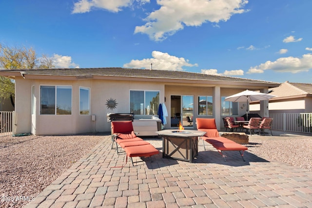 rear view of house featuring a hot tub, an outdoor living space with a fire pit, and a patio area