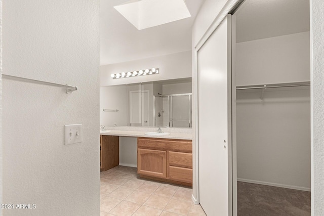 bathroom with vanity, a skylight, tile patterned floors, and walk in shower