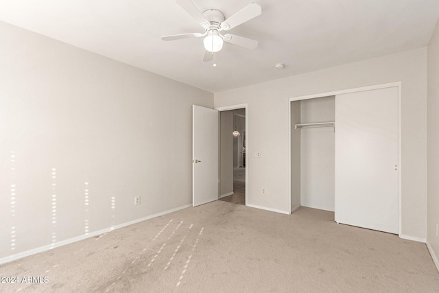 unfurnished bedroom with light carpet, a closet, and ceiling fan