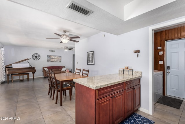 kitchen with light stone countertops, ceiling fan, a textured ceiling, and light tile patterned floors