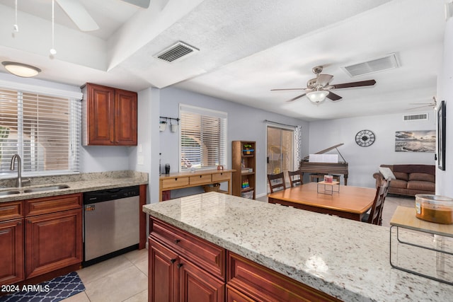 kitchen with dishwasher, sink, light stone countertops, light tile patterned floors, and a textured ceiling