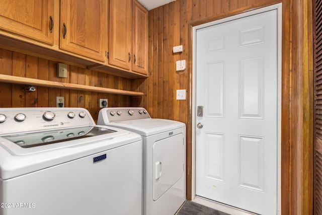 laundry room with wooden walls, washing machine and dryer, and cabinets