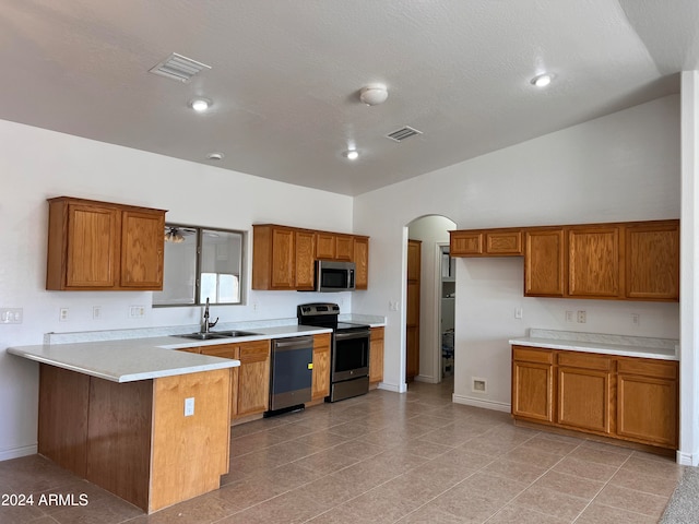 kitchen with vaulted ceiling, kitchen peninsula, a textured ceiling, sink, and appliances with stainless steel finishes