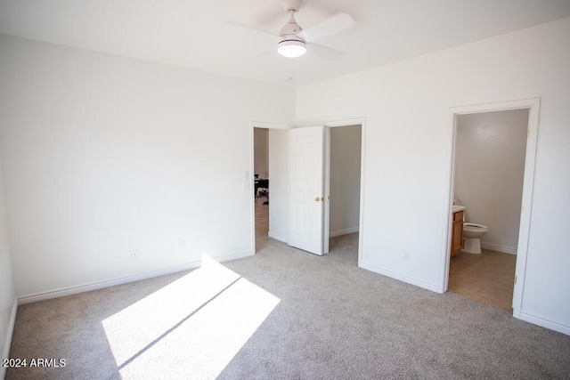 unfurnished bedroom featuring ensuite bathroom, light carpet, and ceiling fan