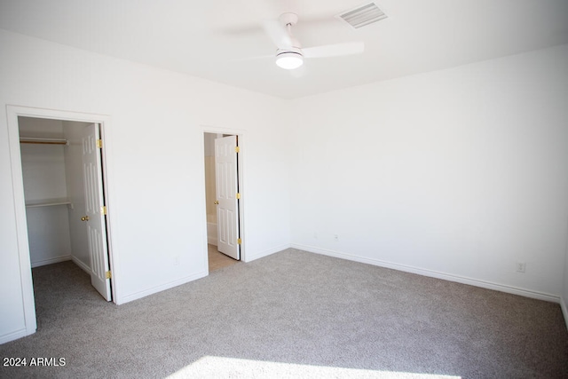 unfurnished bedroom featuring ceiling fan, light carpet, a closet, and a spacious closet