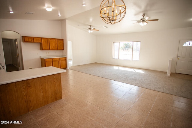 unfurnished living room with lofted ceiling, light carpet, and ceiling fan with notable chandelier