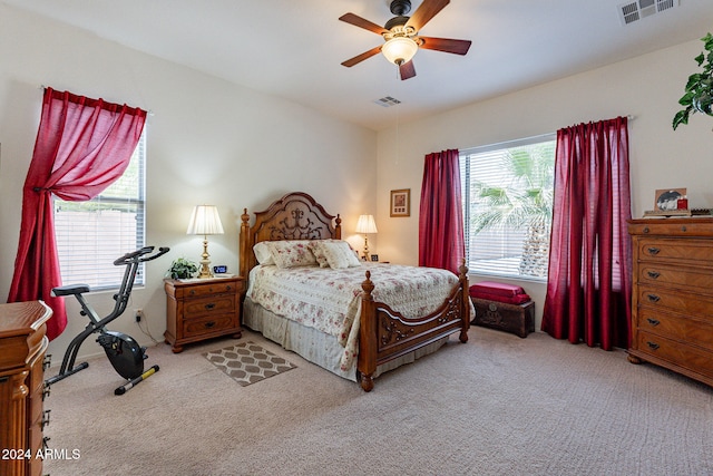 bedroom with light colored carpet, multiple windows, and ceiling fan