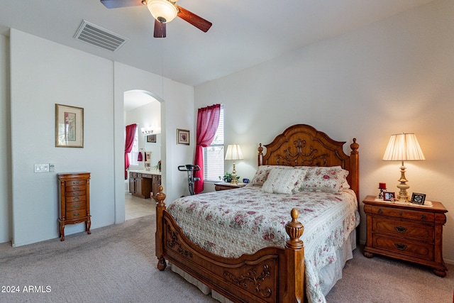 bedroom featuring ceiling fan, ensuite bath, and light carpet