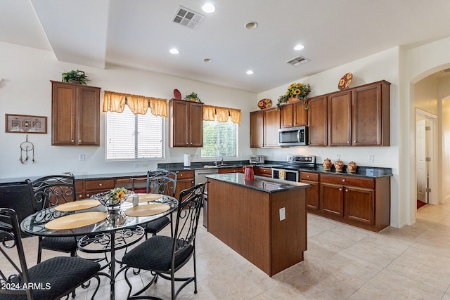 kitchen featuring stainless steel appliances, sink, a kitchen island, and light tile patterned floors