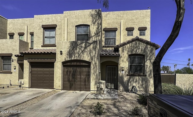 multi unit property featuring fence, driveway, an attached garage, stucco siding, and a tile roof