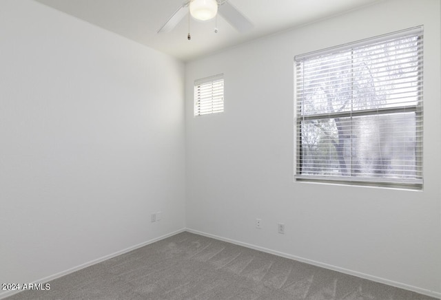 carpeted spare room with a ceiling fan and baseboards