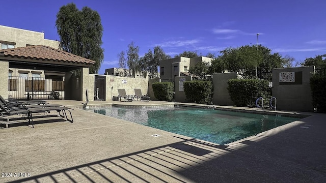 community pool with a patio and fence