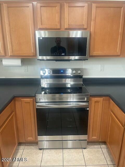 kitchen featuring light tile patterned floors, dark countertops, and appliances with stainless steel finishes