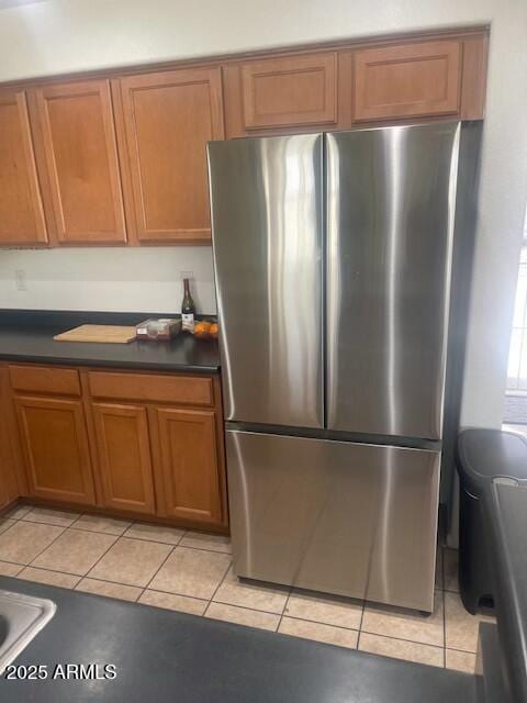 kitchen featuring brown cabinets, dark countertops, and freestanding refrigerator