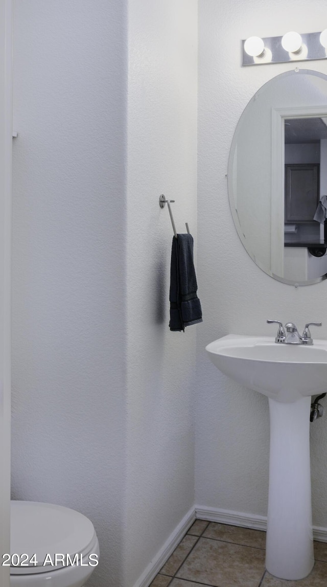 half bathroom with tile patterned flooring, toilet, baseboards, and a sink