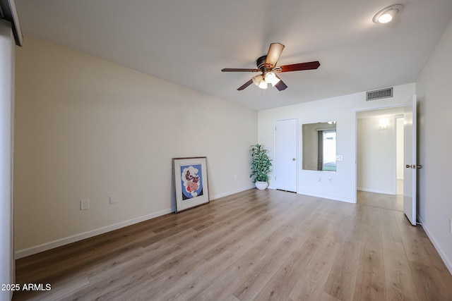 empty room featuring baseboards, visible vents, light wood-style floors, and a ceiling fan