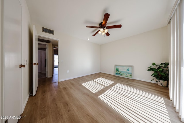 empty room with baseboards, visible vents, wood finished floors, and a ceiling fan