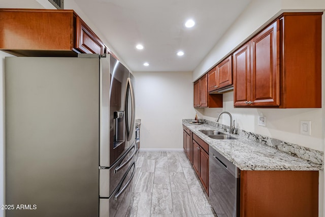 kitchen with recessed lighting, stainless steel appliances, baseboards, a sink, and light stone counters