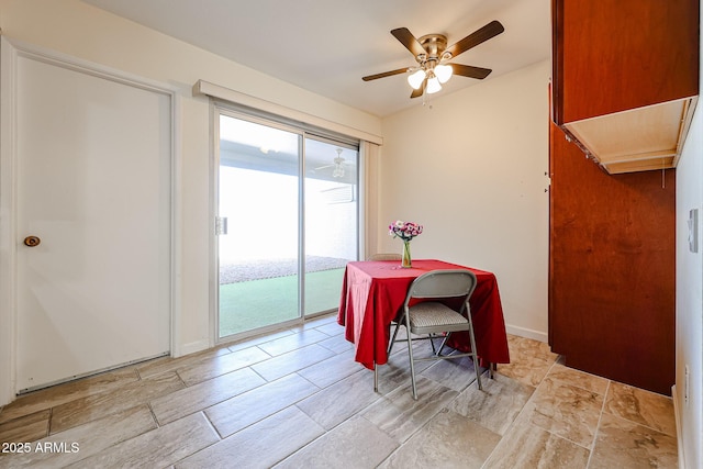 dining room with a ceiling fan and stone finish floor
