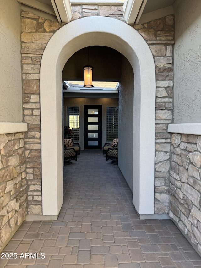 doorway to property with stone siding and stucco siding