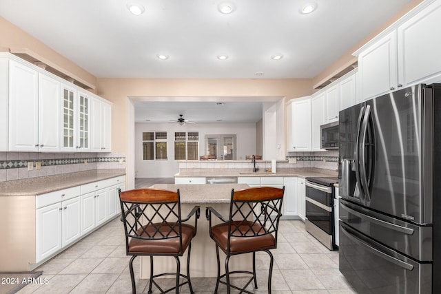 kitchen featuring light tile patterned flooring, appliances with stainless steel finishes, white cabinetry, sink, and kitchen peninsula