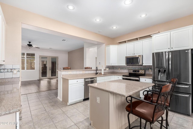 kitchen featuring white cabinetry, stainless steel appliances, a kitchen bar, and kitchen peninsula