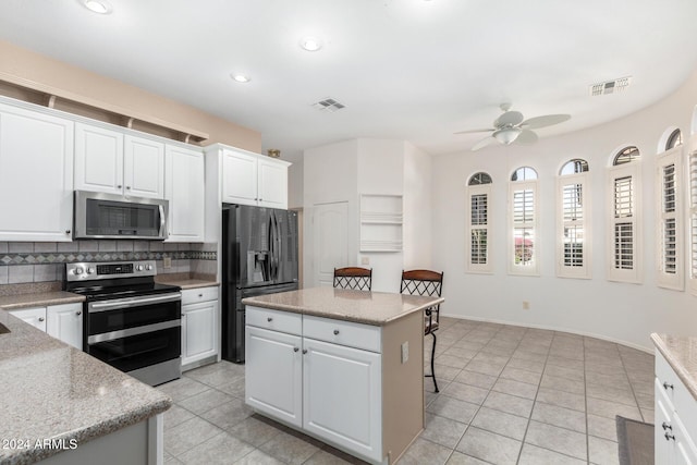 kitchen featuring stainless steel appliances, white cabinetry, a kitchen island, and a breakfast bar