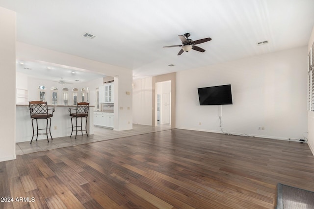 unfurnished living room featuring ceiling fan and dark hardwood / wood-style flooring