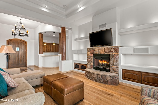 living room with a fireplace, a towering ceiling, a chandelier, and light wood-type flooring