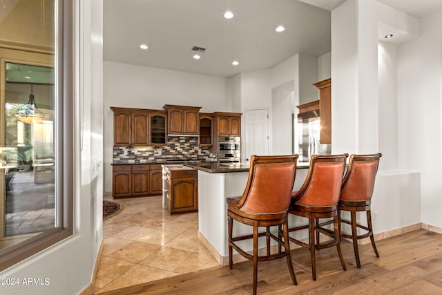 kitchen with a kitchen breakfast bar, backsplash, dark stone countertops, a kitchen island, and appliances with stainless steel finishes