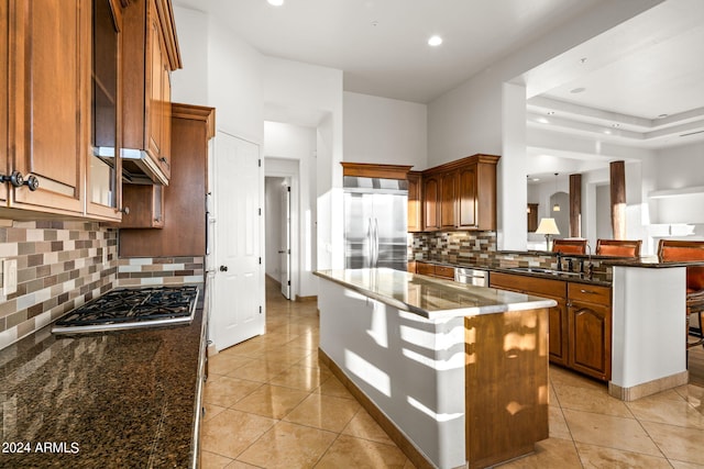 kitchen with a center island, backsplash, sink, dark stone countertops, and stainless steel appliances