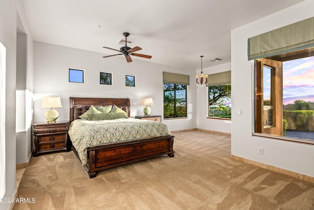 bedroom with ceiling fan with notable chandelier and light colored carpet