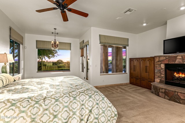 carpeted bedroom featuring a stone fireplace and ceiling fan