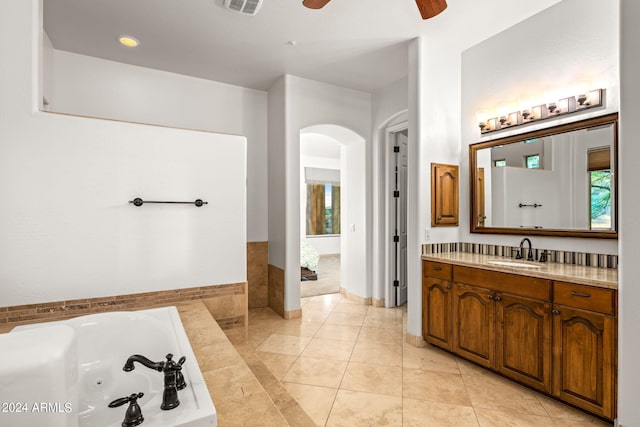 bathroom with tiled tub, ceiling fan, tile patterned flooring, and vanity