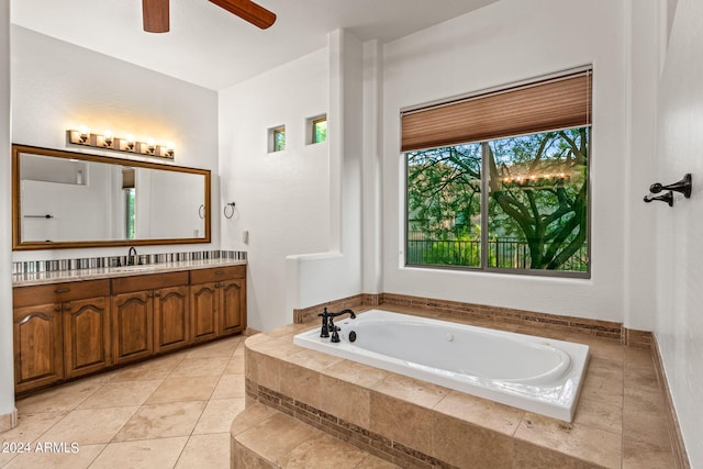 bathroom with tile patterned floors, tiled tub, ceiling fan, and vanity