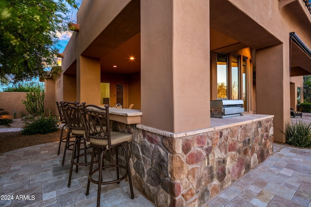 patio terrace at dusk with exterior bar and area for grilling